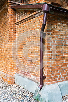 Drainpipe on red brick weathered wall