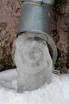 The drainpipes are covered with ice and snow. After a heavy snowstorm, the city is covered with snow and ice. There are many