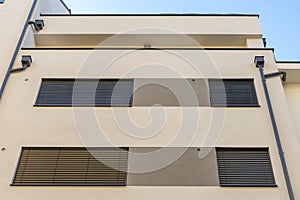 Drainpipes on the wall of a modern residential multi-storey building, the windows are covered with wooden shutters