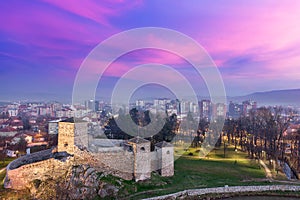 Drama in the sky, ancient fortress and city lights during foggy blue hour