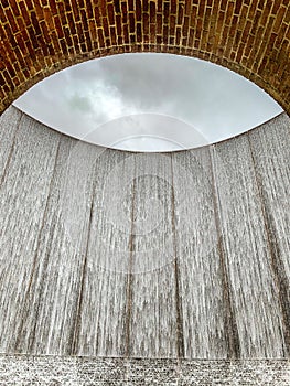 Dramatic 64-foot U-shaped fountain has water rushing down its inside and outside walls.