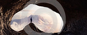 Dramatic Adventurous Scene with Man standing inside a Rocky Cave Landcspae photo