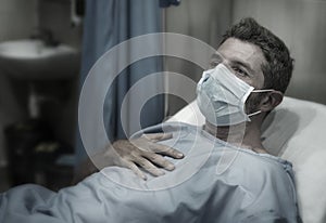Dramatic artistic hospital portrait of attractive and scared man infected by covid19 -  adult male in face mask receiving