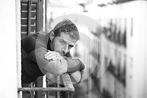 Dramatic artistic portrait of attractive man sad and depressed at home balcony leaning upset feeling worried suffering depression