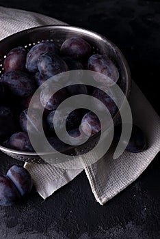 Dramatic autumn still life with plums on a dark background. Rustic