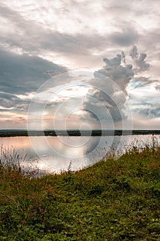 Dramatic beautiful pink blue orange sunset at river with reflection and clouds on natural background