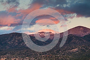 Dramatic, beautiful sunset illuminates the peak of Santa Fe Baldy over a neighborhood in Santa Fe, New Mexico