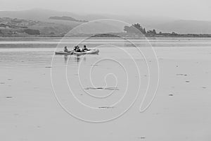 Dramatic black snd white image of tourist kayaking on the California coast enjoying the calm waters of Bodega Bay, California.