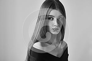 Dramatic black and white portrait of a beautiful lonely girl with freckles isolated on a white background in studio shot