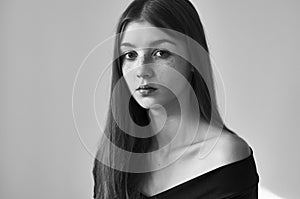 Dramatic black and white portrait of a beautiful lonely girl with freckles isolated on a white background in studio shot