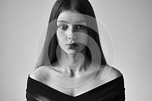 Dramatic black and white portrait of a beautiful lonely girl with freckles isolated on a white background in studio shot