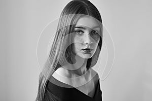 Dramatic black and white portrait of a beautiful lonely girl with freckles isolated on a white background in studio shot