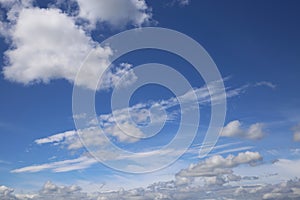 Dramatic blue clear summer sky background, white fluffy cumulus cloud over sea of cirrus clouds