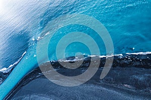 Dramatic blue sea with ripple wave erosion textured on black sand beach