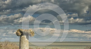 Dramatic blue sky with white clouds over the ruins of an ancient greek column at Histria, on the shores of Black Sea. Histria is