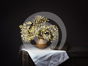 Dramatic chiaroscuro style photo of dried hydrangea flowers with old book on dark background. Melancholy still life with photo