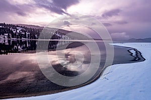 Dramatic clouds during sunrise winter lake with snow and ice