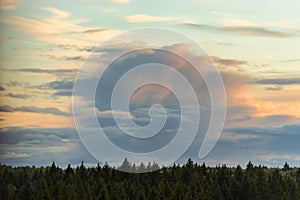 Dramatic cloudscape with cumulus clouds on sky at sunset above the forest horizon