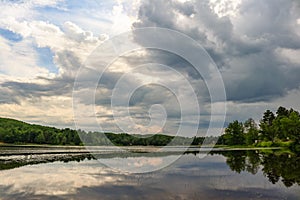 Dramatic cloudscape over the rivers water with trees and patch of blue skies