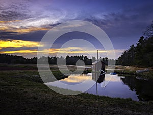 Dramatic cloudscape at sunset and reflections on pump house pond at cranberry bog