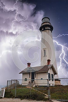 Dramatic coastal lighthouse under lightning storm, California.