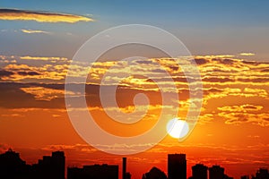 Dramatic colorful fiery red sunset or sunrise sky landscape with line row of city buildings silhouettes . Natural beautiful