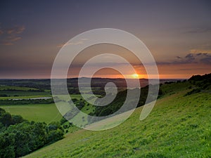 Dramatic and colourful mid-summer sunset over Beacon Hill from Old Winchester Hill in the South Downs National Park near Warnford