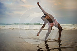 Dramatic contemporary dance choreographer doing ballet beach workout, young attractive and athletic afro black American man