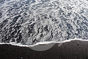 Dramatic contrast between the white sea foam and a black volcanic sand beach as seen from the South Coast in Iceland