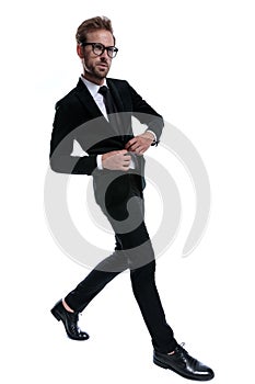 Dramatic cool businessman adjusting suit and confidently walking