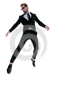 Dramatic cool young man in black suit jumping in the air