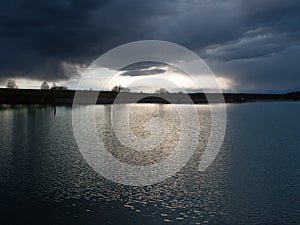 dramatic dark sky over the pond at spring, almost monochrome,siluette