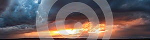 Dramatic dark sunset. Panorama of dark rain clouds in the evening