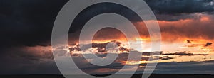 Dramatic dark sunset. Panorama of dark rain clouds in the evening