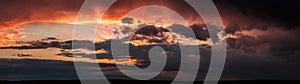 Dramatic dark sunset. Panorama of dark rain clouds in the evening