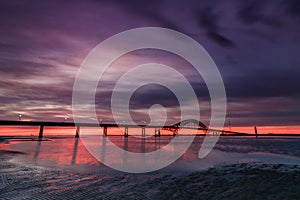 Dramatic deep purple clouds pre dawn over a bridge stretching across a body of water. Fire Island Inlet Bridge - Long Island New Y