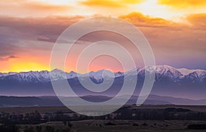 Dramatic early sunrise landscape over carpathian mountains covered in snow with beautiful orange sky and clouds