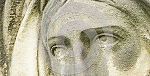 Dramatic eye view of Virgin Mary. Fragment of an ancient stone statue of sad woman in grief