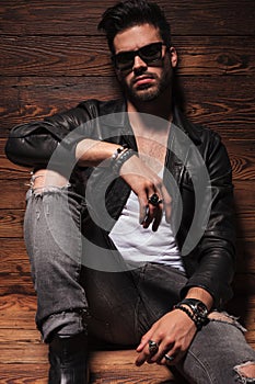 Dramatic fashion man in leather jacket and sunglasses sitting