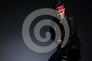 Dramatic fashion model wearing leather jacket on grey background