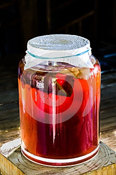 Dramatic image of large jar  of fresh kombucha fermenting with a large scabby growing inside..