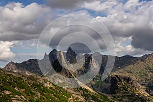 dramatic landscape with big pointy mountain peaks above low clouds