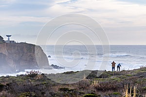 Dramatic landscape of the Pacific Ocean coast, Pillar Point, Half Moon Bay, California; huge waves and surfers visible in the