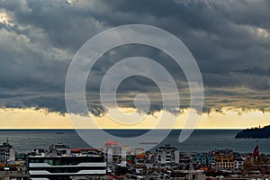 Dramatic landscape of stormy sky over small seaside city. The sky turned yellow before the storm. Dark nimbostratus clouds hang