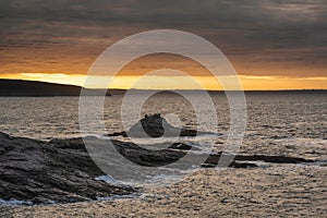 Dramatic landscape sunrise image at Prussia Cove in Cornwall England with atmospheric sky and ocean