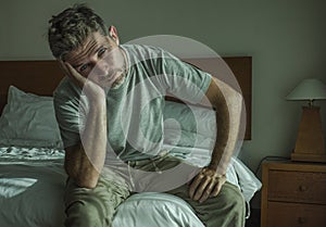 Dramatic lifestyle portrait of 30s to 40s handsome man sitting sad on bed feeling worried and desperate suffering depression