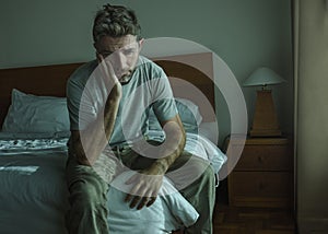 Dramatic lifestyle portrait of 30s to 40s handsome man sitting sad on bed feeling worried and desperate suffering depression