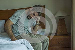 Dramatic lifestyle portrait of 30s to 40s handsome man sitting sad on bed feeling worried and desperate suffering depression