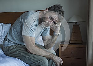 Dramatic lifestyle portrait of handsome guy sitting on bed feeli