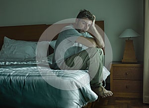 Dramatic lifestyle portrait of handsome guy sitting on bed feeli